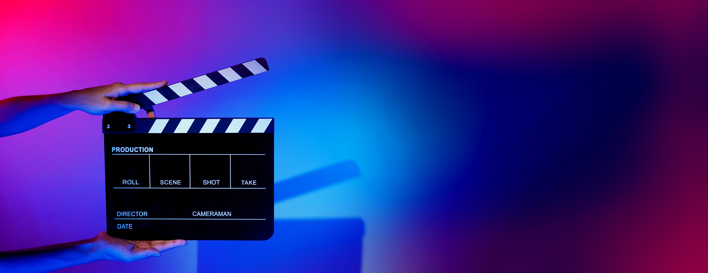 Hand Holds Empty Film Making Clapperboard on Color Background in